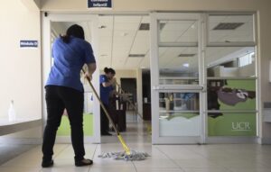 Dos trabajadoras de SELIME trapean el suelo en una oficina de la UCR.