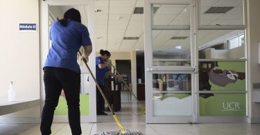 Dos trabajadoras de SELIME trapean el suelo en una oficina de la UCR.